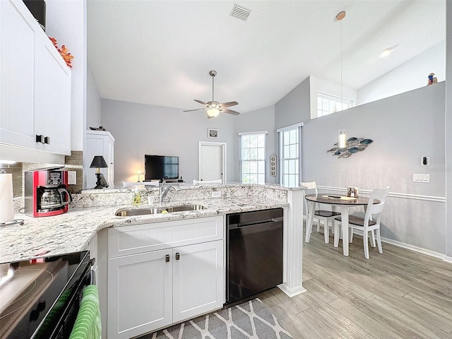 kitchen with black dishwasher, sink, lofted ceiling, stove, and white cabinets