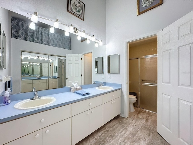 bathroom featuring vanity, toilet, a shower with shower door, and hardwood / wood-style floors