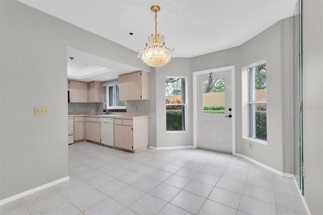 kitchen with white appliances, light brown cabinetry, a textured ceiling, hanging light fixtures, and a chandelier