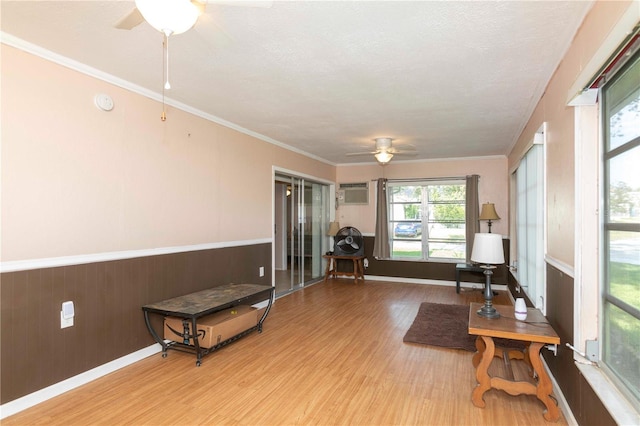 living area featuring light hardwood / wood-style flooring, a textured ceiling, ceiling fan, and crown molding