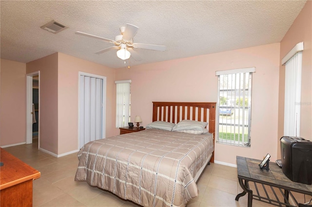 tiled bedroom featuring ceiling fan and a textured ceiling