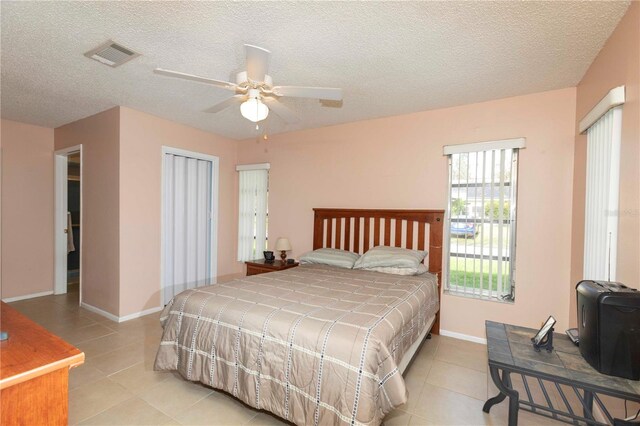 bedroom featuring light tile patterned flooring, a textured ceiling, a closet, and ceiling fan