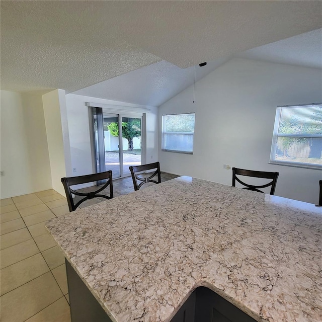 kitchen featuring lofted ceiling, light tile patterned floors, and a textured ceiling