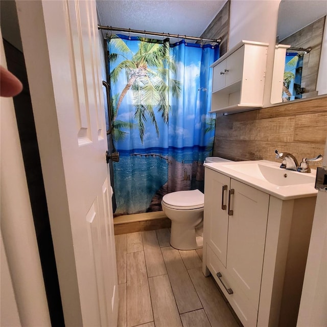 bathroom featuring a shower with curtain, wood walls, vanity, and toilet