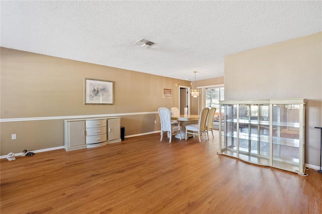 dining area featuring hardwood / wood-style floors, a notable chandelier, and a textured ceiling