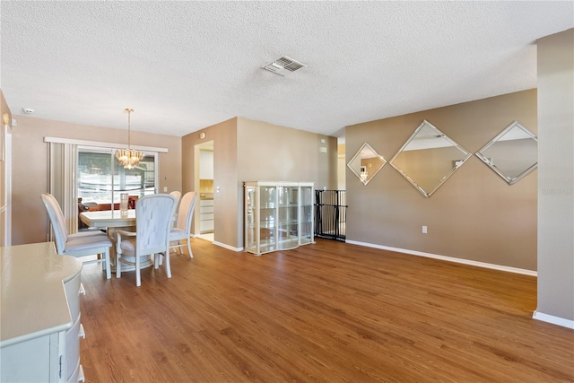 dining room with a notable chandelier, a textured ceiling, and wood-type flooring