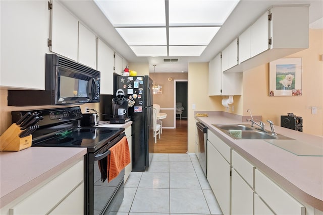 kitchen featuring sink, black appliances, white cabinets, and light tile patterned floors