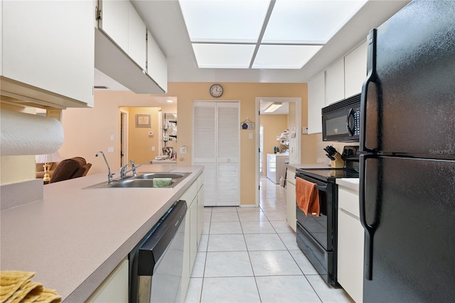 kitchen featuring sink, black appliances, white cabinets, and light tile patterned flooring