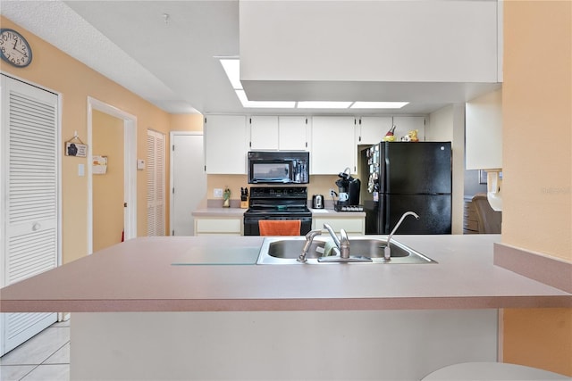 kitchen with kitchen peninsula, white cabinetry, black appliances, and sink