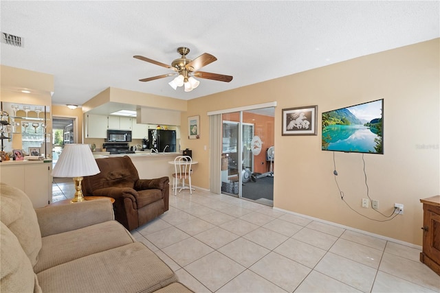 living room with a textured ceiling, light tile patterned flooring, and ceiling fan