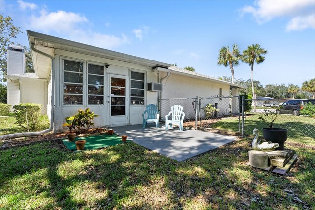 rear view of house featuring a yard, a wall unit AC, and a patio