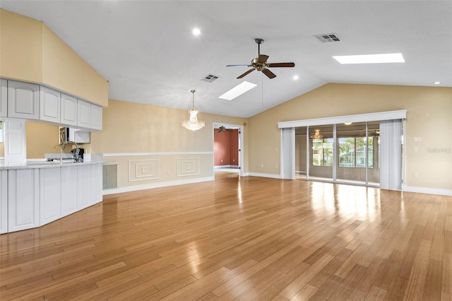 unfurnished living room featuring sink, lofted ceiling, light wood-type flooring, and ceiling fan with notable chandelier