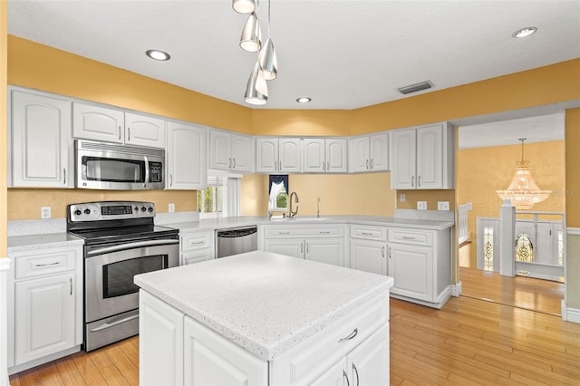 kitchen with light hardwood / wood-style floors, appliances with stainless steel finishes, pendant lighting, and white cabinets