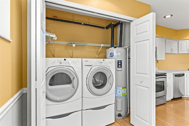 laundry area featuring washing machine and dryer, light hardwood / wood-style flooring, and water heater