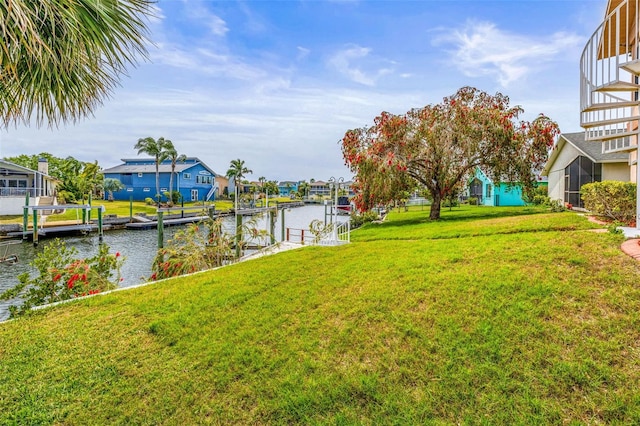 view of yard featuring a residential view, a water view, and a dock
