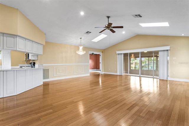 unfurnished living room featuring ceiling fan with notable chandelier, visible vents, and a skylight