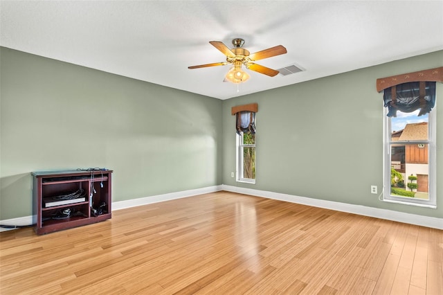 unfurnished living room with plenty of natural light, baseboards, wood finished floors, and a ceiling fan