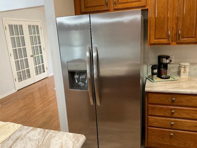 kitchen with stainless steel fridge with ice dispenser and light hardwood / wood-style floors