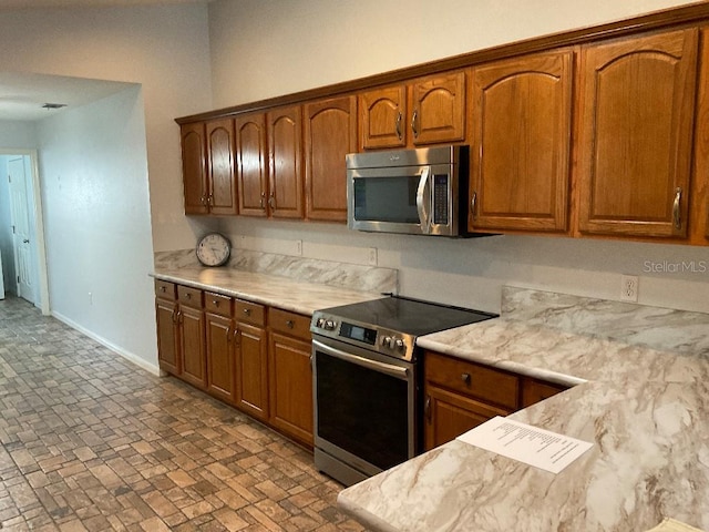 kitchen with appliances with stainless steel finishes and light stone counters