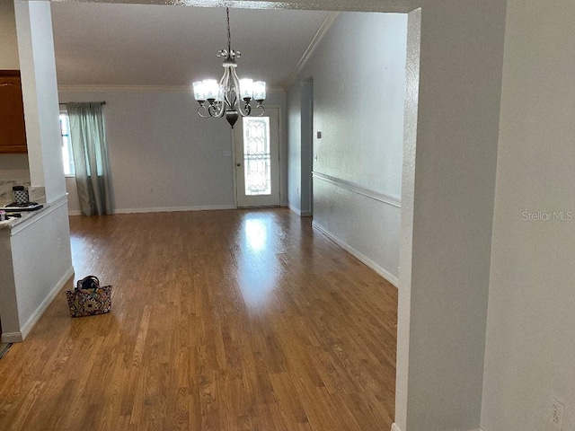 unfurnished dining area featuring crown molding, a notable chandelier, and light wood-type flooring