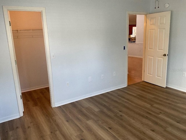 unfurnished bedroom featuring a closet, dark hardwood / wood-style flooring, and a walk in closet