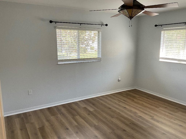 spare room with ceiling fan, a wealth of natural light, and dark hardwood / wood-style floors