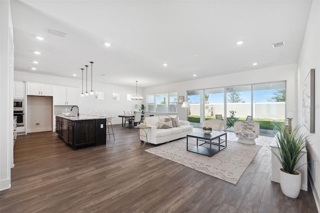 living room featuring sink, an inviting chandelier, and dark hardwood / wood-style flooring