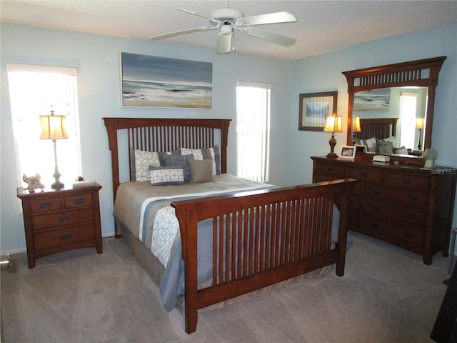 bedroom with light carpet, multiple windows, and ceiling fan