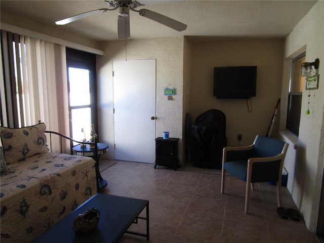 bedroom featuring dark tile patterned flooring, a wood stove, and ceiling fan