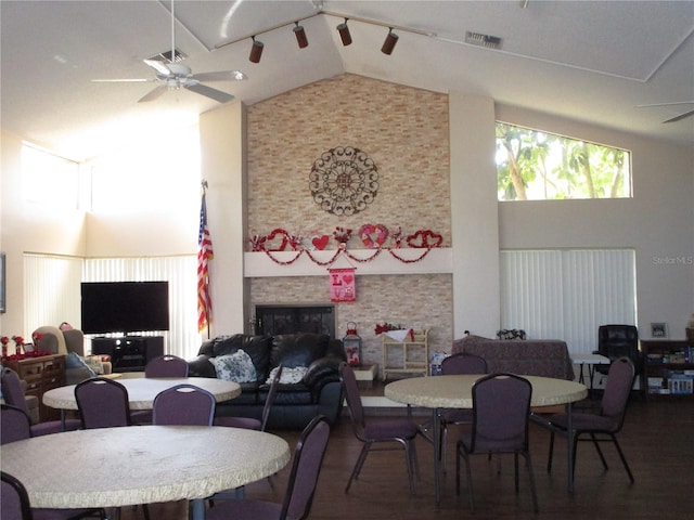 dining room with dark wood-type flooring, a fireplace, high vaulted ceiling, and ceiling fan