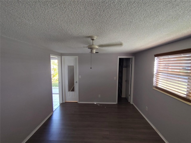 empty room featuring ceiling fan, dark hardwood / wood-style flooring, and a textured ceiling