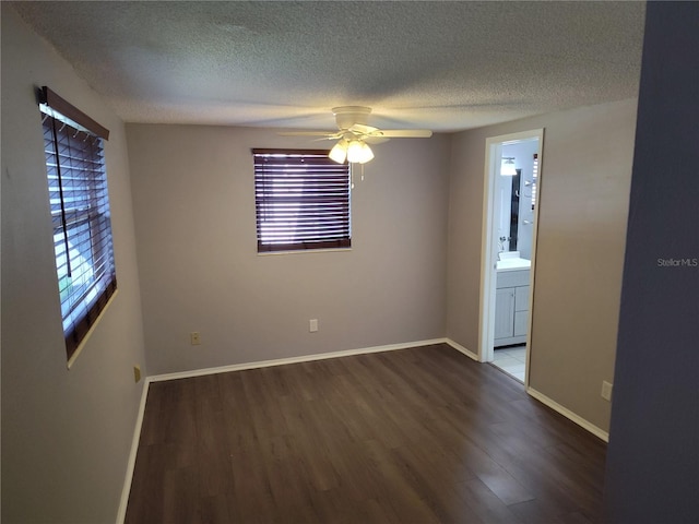 empty room with a textured ceiling, dark hardwood / wood-style flooring, ceiling fan, and a healthy amount of sunlight