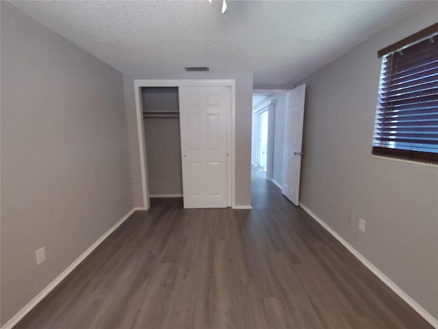 unfurnished bedroom with a closet, dark wood-type flooring, and a textured ceiling