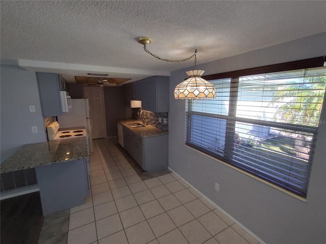 kitchen with sink, kitchen peninsula, dark stone countertops, a textured ceiling, and light tile patterned flooring