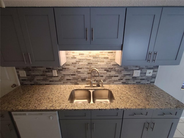 kitchen featuring backsplash, light stone counters, sink, and dishwasher