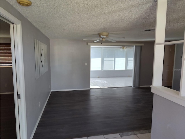 unfurnished room featuring visible vents, baseboards, a ceiling fan, a textured ceiling, and wood finished floors