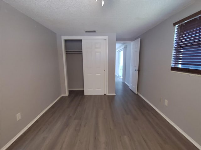 unfurnished bedroom featuring a closet, baseboards, wood finished floors, and a textured ceiling