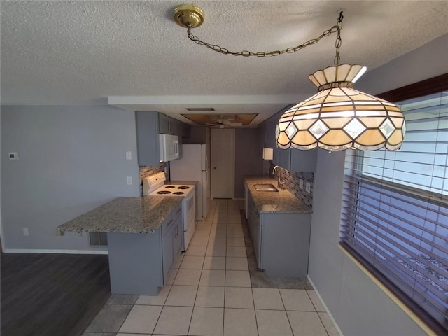 kitchen featuring light tile patterned floors, a sink, white appliances, a peninsula, and light stone countertops