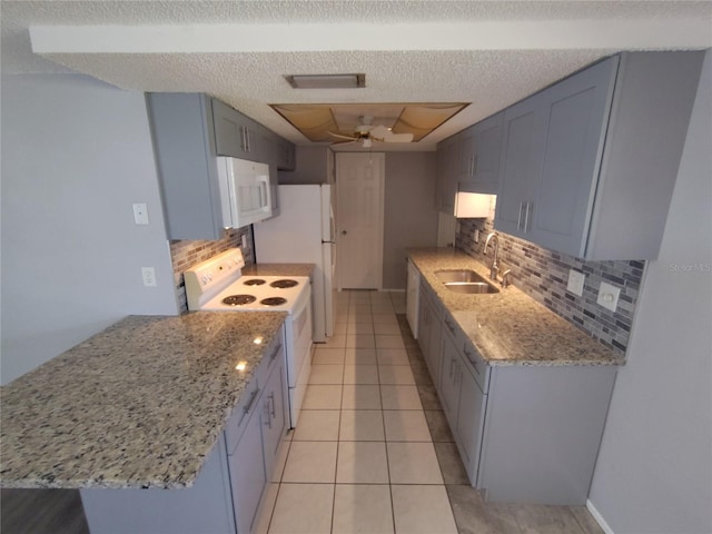 kitchen featuring light tile patterned floors, a sink, a ceiling fan, white appliances, and light stone counters