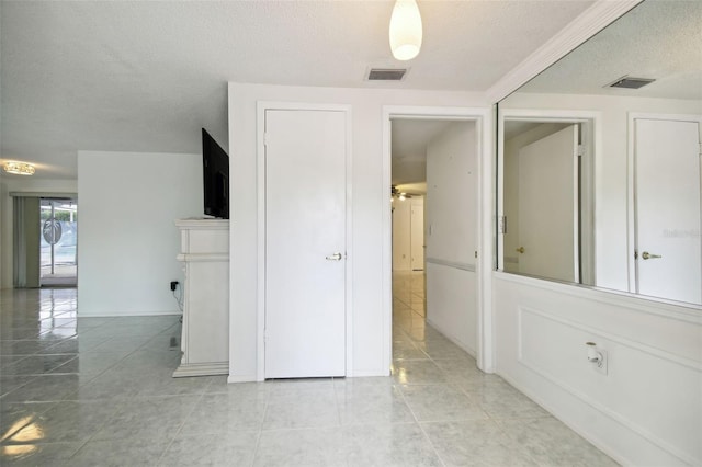 spare room with a textured ceiling and light tile patterned flooring