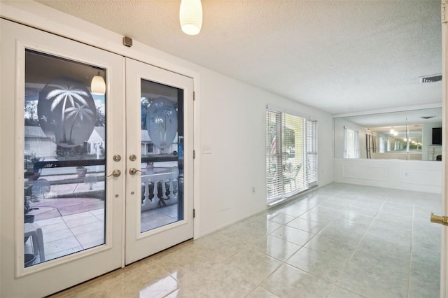 doorway to outside featuring french doors, a textured ceiling, and light tile patterned floors