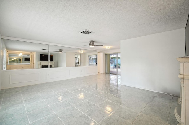 tiled spare room with a textured ceiling and ceiling fan