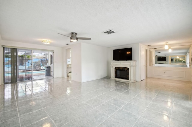 unfurnished living room featuring a textured ceiling, light tile patterned floors, and ceiling fan