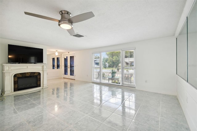 unfurnished living room featuring french doors, a textured ceiling, light tile patterned floors, and ceiling fan