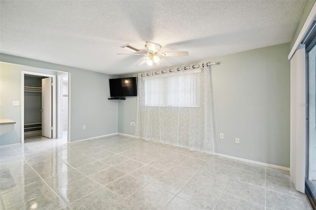 tiled empty room featuring a textured ceiling and ceiling fan