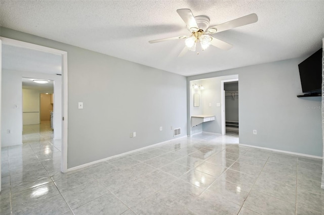 interior space featuring a closet, a walk in closet, light tile patterned floors, a textured ceiling, and ceiling fan