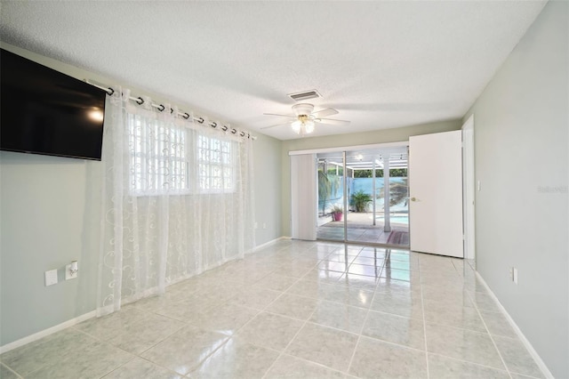 tiled spare room with a textured ceiling and ceiling fan