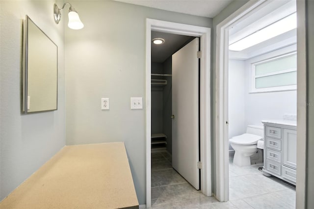 bathroom with toilet, vanity, and tile patterned flooring