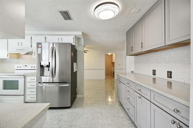 kitchen featuring stainless steel refrigerator with ice dispenser, white electric stove, light tile patterned floors, and backsplash