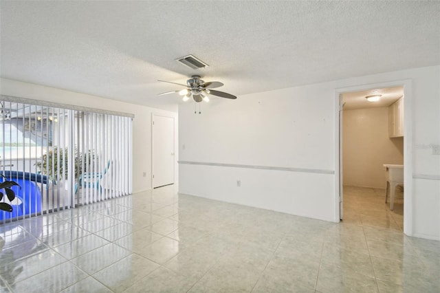 spare room featuring a textured ceiling, light tile patterned floors, and ceiling fan